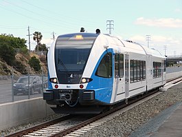 A railcar on a rail line in the median of a highway