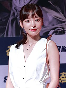 Goo, in a white dress, smiles and faces forward