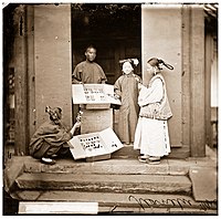 1869年，John Thomson在北京拍摄的照片。梳着二把头的旗人妇女展示的商品是女性佩戴的绒花。