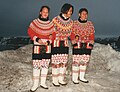 Kvinner i grønlandske folkedrakter med blondekanta kamikkar.