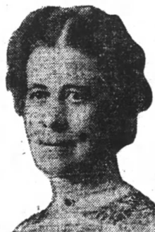A newspaper photograph of a middle-aged white woman with dark hair, center parted and dressed back to the nape
