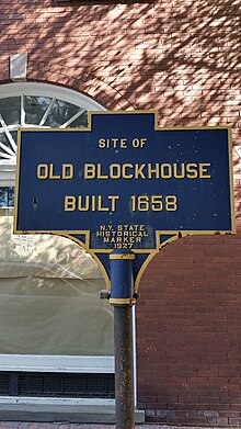 a picture of the marker with the stone Senate house behind it