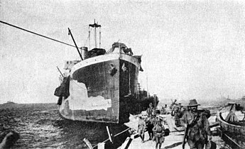 Soldiers of the Australian 2nd Infantry Brigade disembarking at V Beach on 6 May 1915, for the Second Battle of Krithia. River Clyde is beached and serving as a quay. The light coloured patch on her starboard bow is part of her unfinished yellow camouflage.