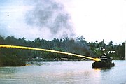 Riverboat of the U.S. brownwater navy firing napalm at an onshore target during the Vietnam War.
