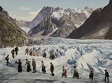 Représentation artistique d'une vingtaine d'hommes et femmes, en costume d'époque, traversant un glacier.