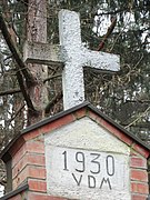 Priekyje, virš atiko, įtaisytas kryžius su data ir inicialais („Vytauto Didžiojo Metai“)