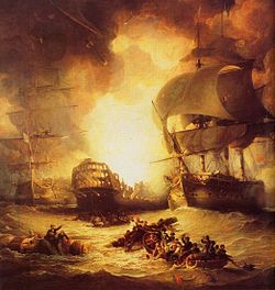 On a choppy sea, a large warship burns out of control. The central ship is flanked by two other largely undamaged ships. In the foreground two small boats full of men row between floating wreckage to which men are clinging.