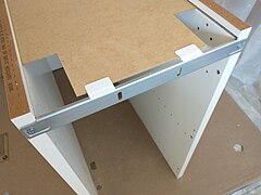 The back panel locks into channels. Only in a base cabinet the top is attached to a top rail.