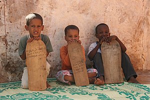 Young boys taking Qur'an lessons from wooden t...
