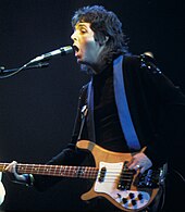 Coloured image of a long-haired McCartney in the 70s playing a guitar.