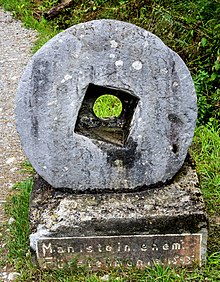 Aufgestellter Mahlstein am Wegesrand mit Hinweisschild: Mahlstein ehemalige Fürstenmühle 1543