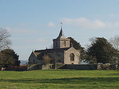 Stone building with square tower topped by a small spires.