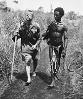 Australský voják George „Dick“ Whittington, je podpírán Papuáncem Raphaelem Oimbarim, poblíž Buny dne 25. prosince 1942. Whittington zemřel v únoru 1943 na následky tyfu.