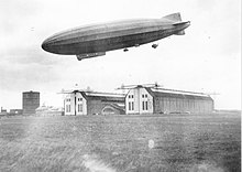 Airship flying over two giant hangars