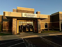 Изображена передняя часть библиотеки филиала Nixa. Библиотека кирпичная и сразу встречается с парковкой.