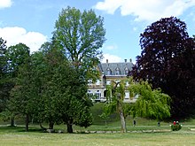 Photographie d'une vaste demeure entourée de verdure