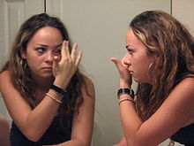 Young woman removing contact lenses from her eyes in front of a mirror Contact Lens Girl.jpg