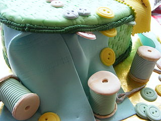 Un pastel cubierto de fondant, que representa un kit de costura.