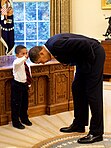 United States President Barack Obama bends down to allow the son of a White House staff member to touch his head (cropped).jpg