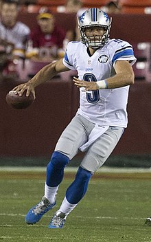 Matthew Stafford in a Detroit Lions uniform and helmet. He's on a football field preparing to throw a pass.