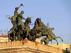 The bronze "Quadriga with Apollo and Euterpe" (the muse of lyric poetry) on the Teatro Politeama (1867–1874) in Palermo (Italy) by sculptor Mario Rutelli with riders on the sides fashioned by Benedetto Civiletti.