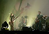На сцене - мужская группа, состоящая из двух MC, двух клавишников и гитариста. Некоторые из толпы с руками в воздухе присутствуют на переднем плане