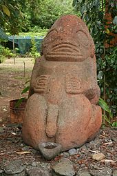 Photographie d'une statue de Tiki en pierre rouge.