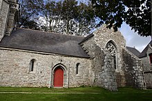 À gauche, porte encadrée de minuscules fenêtres très étroites. À droite, le croisillon avec sa grande fenêtre et ses deux gigantesques contreforts.