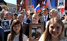 Putin participating in the Immortal Regiment, with participants holding the images of their relatives who fought in the War Immortal Regiment in Moscow (2018-05-09) 11.jpg