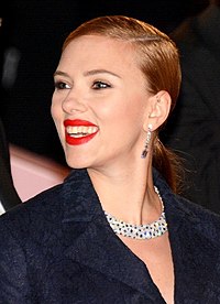 Scarlett Johansson, wearing a dark blue coat, smiles to her left.