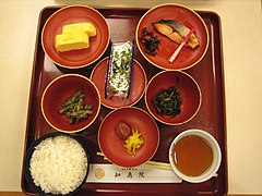 A traditional Japanese breakfast of rice, pickles (umeboshi and takuan), grilled salmon, egg, nori, and vegetables