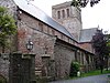 A stone church seen from an angle, with a clerestory and a large central tower with a plain parapet