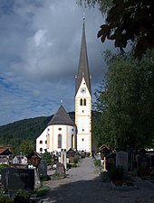 Photographie d'une église de forme longiligne, située derrière un cimetière.