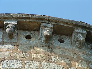 Couronnement de l'abside avec des modillons à têtes grimaçantes et des métopes percés de trous ronds