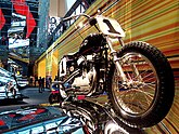 Netuŝitaj 1960-aj jaroj Harley-Davidson-voĉtordilstilmotorciklo muntita kvazaŭ rajdante super ruliĝanta reflekta ŝtalsurfaco.