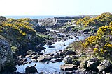 Bun na hAbhann – Flussmündung mit Kaimauer und dahinter das Wasser der Galway-Bucht;er Fluss ist nur 7 km lang und entspringt weiter oben im Loch Ghleann Daimh