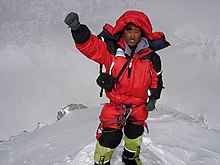 osoba v červeném péřovém overalu na vrcholu hory