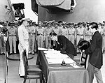 Mamoru Shigemitsu, le ministre des Affaires étrangères du Japon, signe les actes de capitulation du Japon à bord du USS Missouri sous le regard du général Richard K. Sutherland.