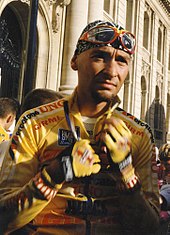 A cyclist unzipping his yellow cycling jersey.