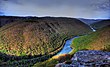 An overlook view of a green forested gorge with a river meandering through it.