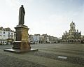 Achterkant standbeeld met op de achtergrond het Stadhuis van Delft