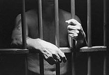 Black and white photograph of a man behind bars