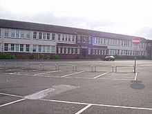 Partial view of two-storey school building and its main entrance