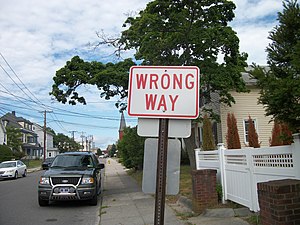 A reverse-colors "Wrong Way" sign on...