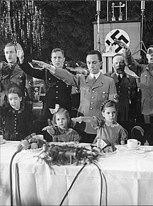 Joseph Goebbels with his daughters, Hilde (center) and Helga (right), at a Christmas celebration in the Saalbau (Hall) Friedrichshain, Berlin, 1937, during the singing of the national anthems Bundesarchiv Bild 183-C17887, Berlin, Joseph Goebbels mit Kindern bei Weihnachtsfeier.jpg
