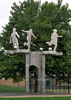 Pamětní monument na místě bývalého stadionu, který znázorňuje tři driblující fotbalisty