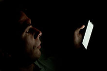 Smartphone usage can disturb sleep and cause vision problems. Person looking at smartphone in the dark (2).jpg