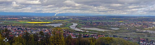 Blick nach Nordosten mit Barkhausen (vorne), diagonal fließender Weser, Grüner Brücke Neesen (alte Eisenbahnbrücke), Brücke der B 65 (hinten) und jenseits des Flusses liegender Ortschaft Neesen, links oben Minden, im Hintergrund die Rauchfahne vom Kraftwerk Heyden