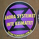 Extinction Rebellion klistermärke i Uppsala: "Ändra systemet inte klimatet".