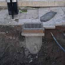 Storm drain with its pipe visible beneath it due to construction work Storm drain pipe (crop).JPG
